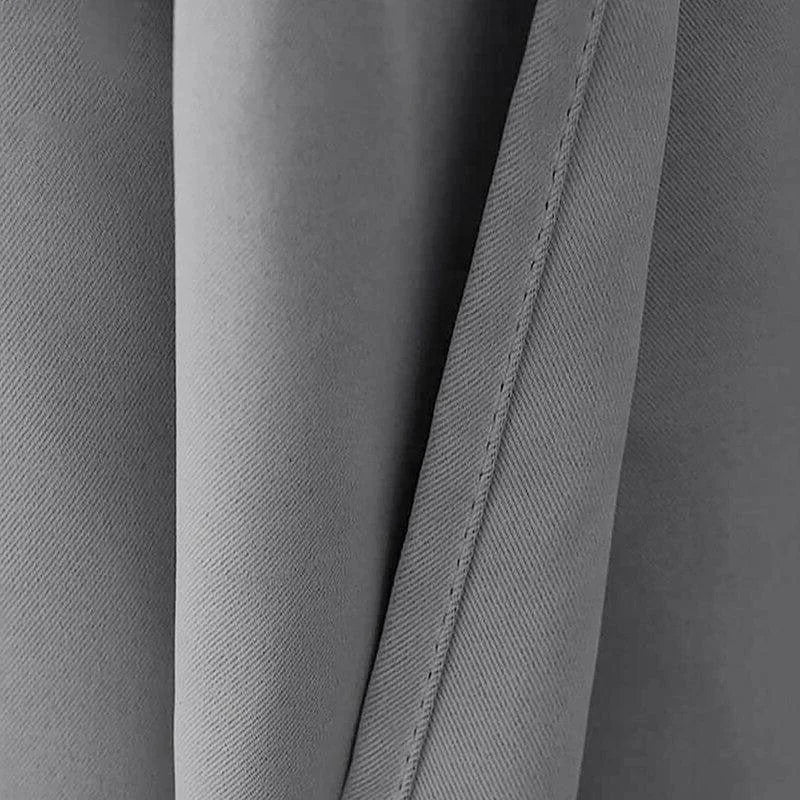 Gros plan sur un rideau gris, présentant des plis élégants et une couture fine. Ce rideau apportera une touche contemporaine à votre décoration intérieure, idéal pour créer une ambiance moderne et épurée. Parfait pour les salons, chambres ou bureaux, ajoutant une touche de sophistication minimaliste.