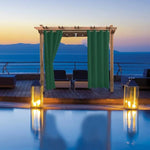Ensemble de rideaux d'extérieur vert pour pergola, créant une ambiance élégante et intime sur une terrasse en bois avec vue imprenable sur un coucher de soleil. Idéal pour profiter des soirées estivales près de la piscine, offrant confort et style. Accessoire parfait pour décorer un espace extérieur tout en préservant l'intimité.