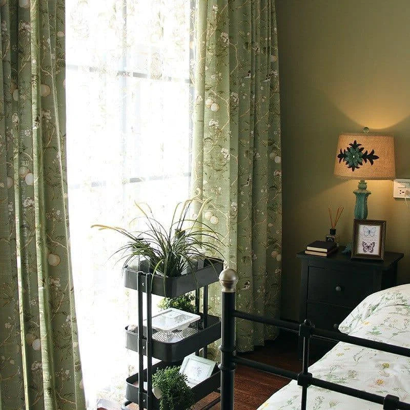 Chambre lumineuse et élégante avec rideaux verts à motifs floraux, mettant en valeur une décoration intérieure harmonieuse. Table de nuit avec lampe design et livres, parfaite pour créer une atmosphère relaxante et accueillante. Plantes d'intérieur apportant une touche de nature pour un espace serein et zen.