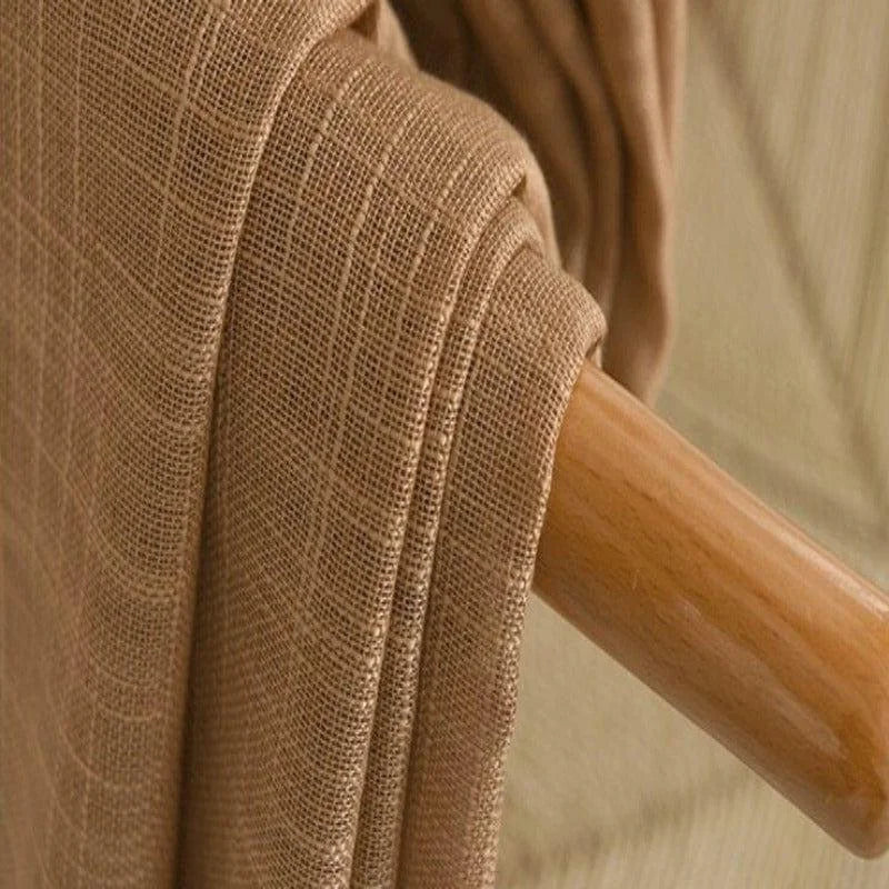 Étoffe beige suspendue sur un porte-manteau en bois, offrant une touche naturelle et élégante à toute décoration intérieure. Style moderne et intemporel idéal pour un salon ou une chambre à coucher. Accessoire polyvalent pour ameublement et décoration.