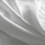 Image d’un tissu blanc ondulé, idéal pour la décoration intérieure ou la confection de vêtements élégants. Sa texture douce et luxueuse offre un aspect raffiné à tous vos projets créatifs.
