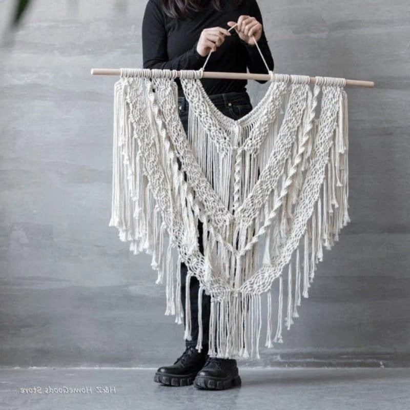 Décoration murale en macramé de style bohème suspendue à une tige en bois. Élément décoratif idéal pour apporter une touche artistique et élégante à votre intérieur. Conçu avec des motifs complexes et des franges, ce macramé s’adapte parfaitement à un salon moderne ou une chambre cosy.