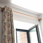 Tringle à rideaux élégante avec rideaux à motifs floraux, installée au-dessus d'une fenêtre ouverte, idéale pour une décoration intérieure moderne et chaleureuse.