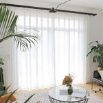 Rideaux blancs élégants pour salon moderne avec grandes fenêtres, meubles contemporains et plantes vertes, apportant une atmosphère lumineuse et naturelle à votre intérieur.