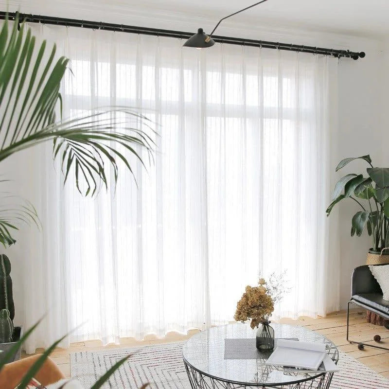 Rideaux blancs élégants pour salon moderne avec grandes fenêtres, meubles contemporains et plantes vertes, apportant une atmosphère lumineuse et naturelle à votre intérieur.