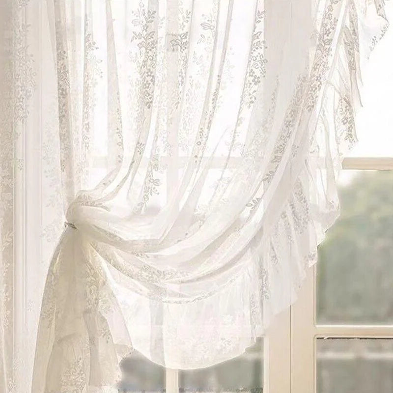 Rideau décoratif blanc avec des motifs floraux en transparence, suspendu élégamment devant une fenêtre, offrant une ambiance lumineuse et aérienne à la pièce.