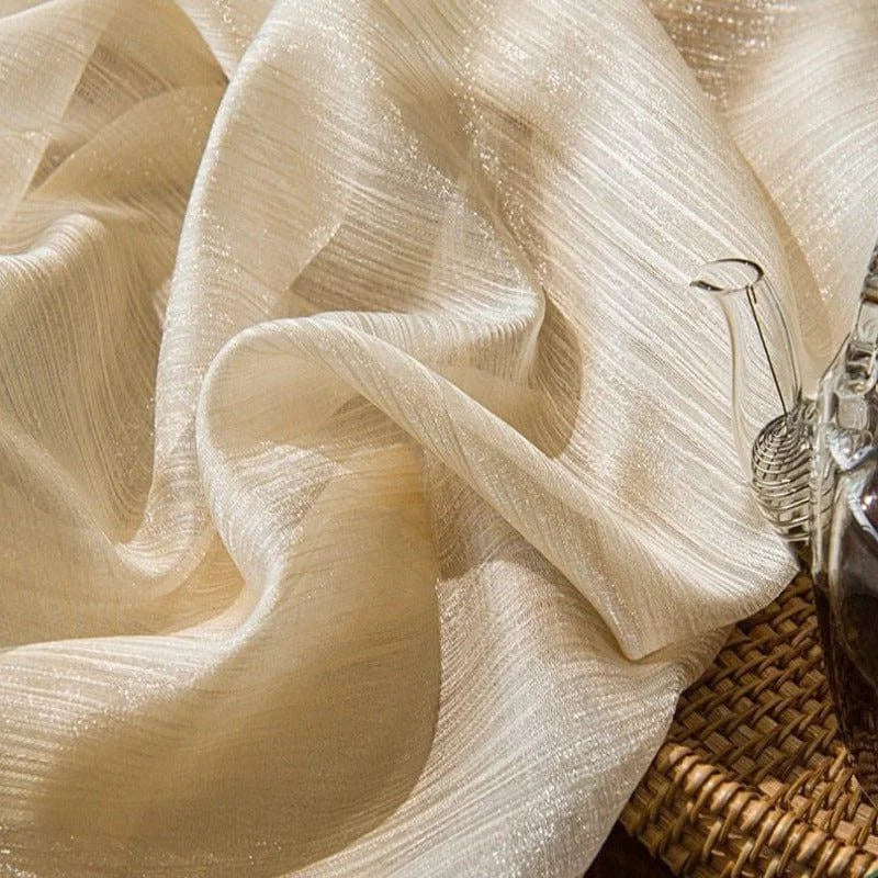 Tissu beige élégant drapé sur une surface, idéal pour la décoration intérieure et la création d'ambiance chaleureuse. Parfait pour les rideaux ou nappes raffinées.