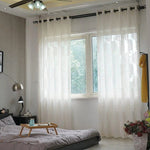 Chambre moderne avec rideaux blancs transparents offrant une ambiance lumineuse, dotée d'un lit confortable et d'une table de nuit, parfaite pour créer un espace cosy et apaisant.