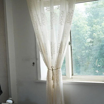 Rideau élégant avec motif floral suspendu à une fenêtre ensoleillée. Décoration intérieure élégante, parfait pour ajouter une touche de sophistication et de luminosité à votre salon ou chambre.  Accessoire idéal pour créer une ambiance chaleureuse et accueillante dans votre espace de vie.