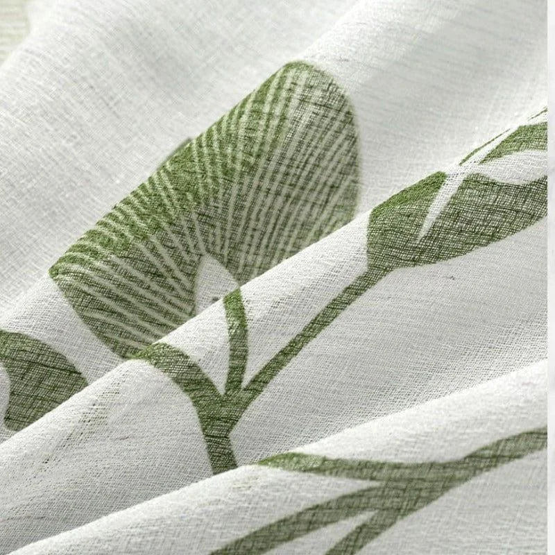 Gros plan sur un tissu blanc à motifs végétaux verts, idéal pour une décoration intérieure naturelle et apaisante. Parfait pour des rideaux, nappes ou housses de coussin, ajoutant une touche de fraîcheur et d'élégance à votre pièce. Découvrez ce design floral subtil et moderne pour transformer votre espace de vie.