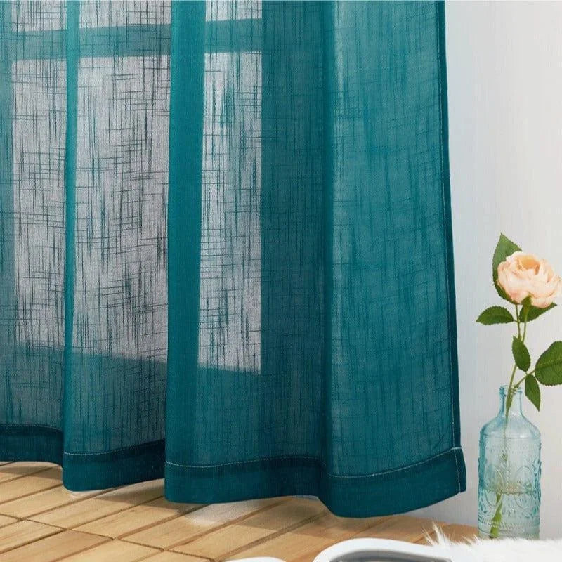 Rideau bleu élégant devant une fenêtre, créant une ambiance lumineuse et aérée. Décoration parfaite pour ajouter une touche de couleur à votre intérieur. Notez la présence d'une rose dans un vase, ajoutant une touche de nature à l'ensemble. Idéal pour le salon ou la chambre à coucher.