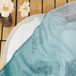 Voile léger bleu drapé sur une table en bois, avec des fleurs blanches délicates dans un vase, parfait pour un décor élégant et minimaliste. Accessoire idéal pour sublimer votre intérieur avec une touche de fraîcheur et de sophistication naturelle.