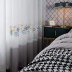 Rideaux élégants avec motifs floraux bleus et jaunes, idéal pour une chambre chic. Décoration intérieure moderne avec table de chevet verte, lampe élégante et papier peint texturé. Parfait pour apporter une touche de charme et de sophistication à votre espace de vie.
