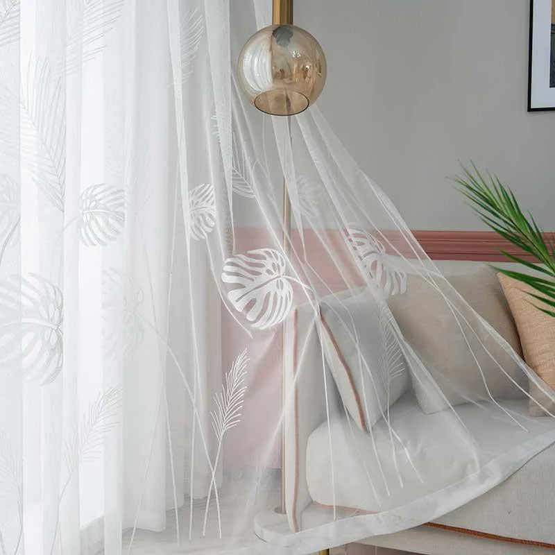Voilage blanc élégant avec motifs de feuilles tropicales, idéal pour un salon moderne. Apporte une touche de légèreté et de sophistication à votre intérieur tout en laissant entrer la lumière naturelle. Accessoire de décoration essentiel pour un espace de vie chaleureux et accueillant.