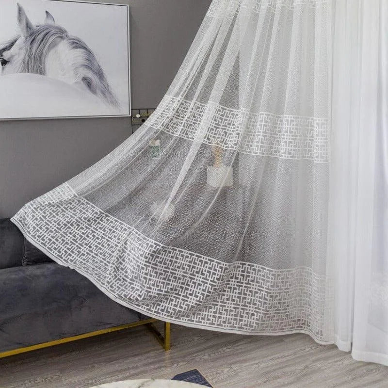 Voilage blanc élégant avec motifs géométriques pour salon moderne. Ce rideau léger apporte une touche de sophistication tout en permettant à la lumière naturelle de sublimer votre espace intérieur. Idéal pour créer une ambiance chaleureuse et accueillante, ce voilage s'intègre parfaitement à tout type de décoration contemporaine.