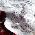 Détail d'un textile décoratif avec motif floral délicat et perle, idéal pour ajouter une touche élégante à votre décoration intérieure ou confectionner des accessoires de mode uniques.