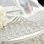 Nappe élégante avec bordure en dentelle sur une table décorée de fleurs blanches, idéale pour ajouter une touche de sophistication à votre salle à manger. Parfait pour les événements spéciaux et les décorations de table raffinées.