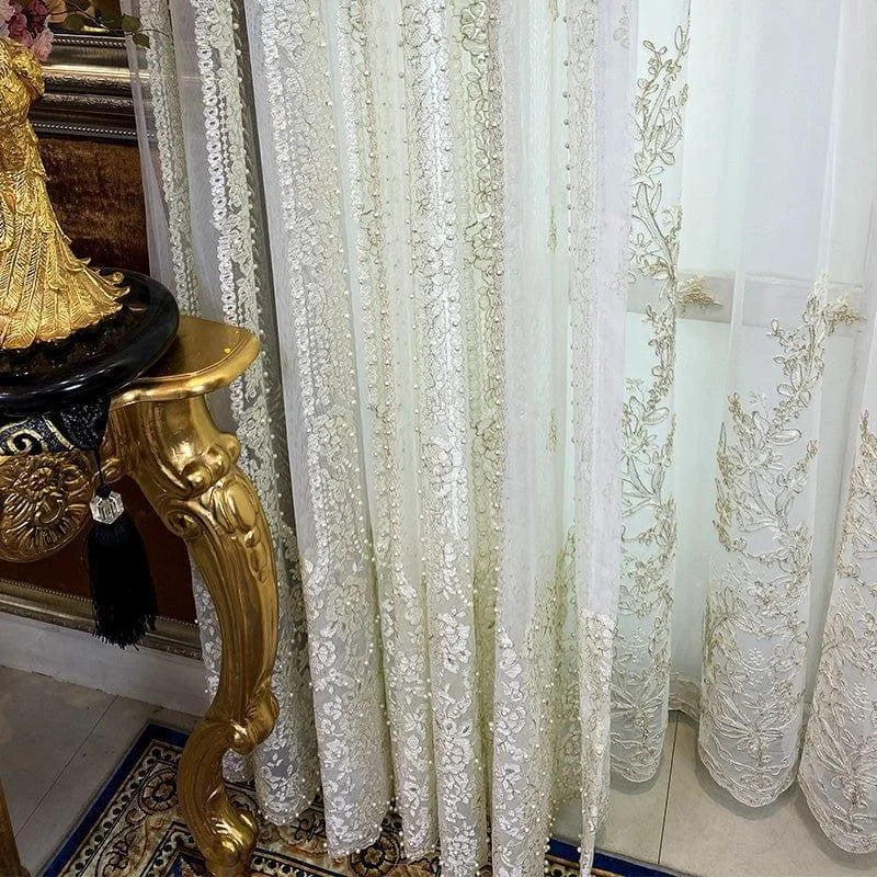 Rideaux élégants avec broderies détaillées, décorant un intérieur raffiné. Ces rideaux ajoutent une touche de sophistication et de style, parfaits pour un salon luxueux ou une salle à manger distinguée. Motifs floraux délicats soulignant le charme classique de la pièce. Accessoire idéal pour sublimer votre décoration d'intérieur.