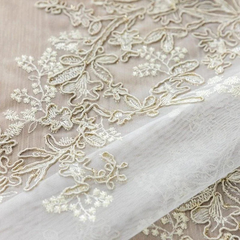 Motif floral délicat sur tissu transparent idéal pour robes de mariée ou décorations élégantes, soulignant un design sophistiqué et raffiné. Parfait pour un look romantique et intemporel.