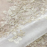 Motif floral délicat sur tissu transparent idéal pour robes de mariée ou décorations élégantes, soulignant un design sophistiqué et raffiné. Parfait pour un look romantique et intemporel.