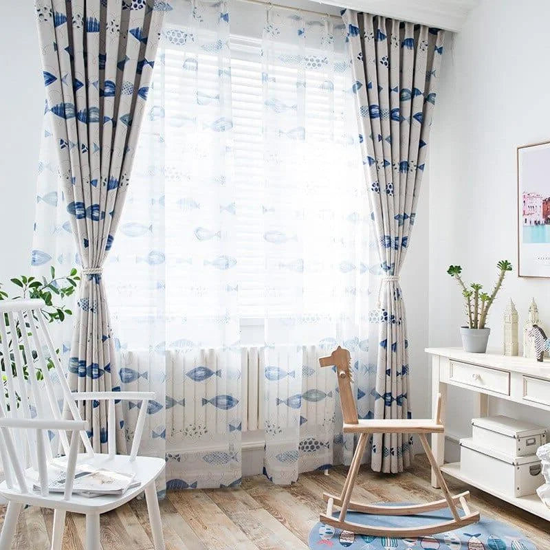 Rideaux élégants à motif de poissons bleus, apportant une touche marine et moderne à la décoration intérieure. Accent parfait pour une ambiance lumineuse et aérée dans une chambre d’enfant ou un salon, avec un fauteuil à bascule en bois et un bureau blanc complétant l’ensemble du décor épuré.