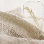 Gros plan sur un tissu raffiné avec motif texturé, idéal pour la décoration intérieure élégante et moderne. Ce produit offre une esthétique naturelle et douce, parfait pour ajouter une touche d'élégance à tout espace.
