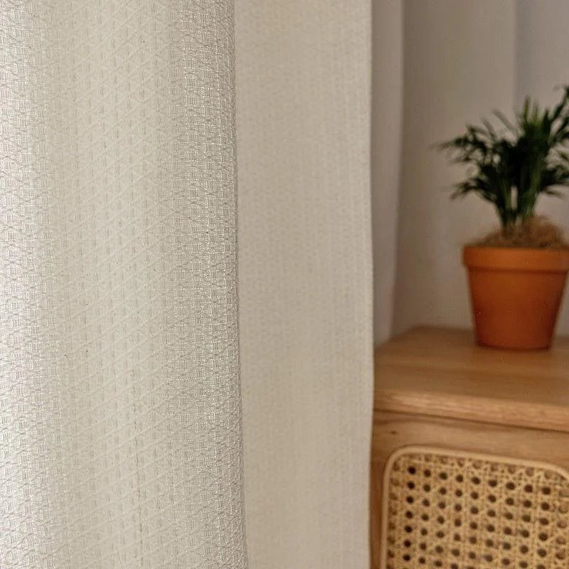 Rideau blanc à motif géométrique moderne, parfait pour ajouter une touche d'élégance à votre intérieur. Ce rideau s'harmonise parfaitement avec une décoration végétale et un mobilier en bois, créant une ambiance chaleureuse et apaisante dans votre salon ou chambre.