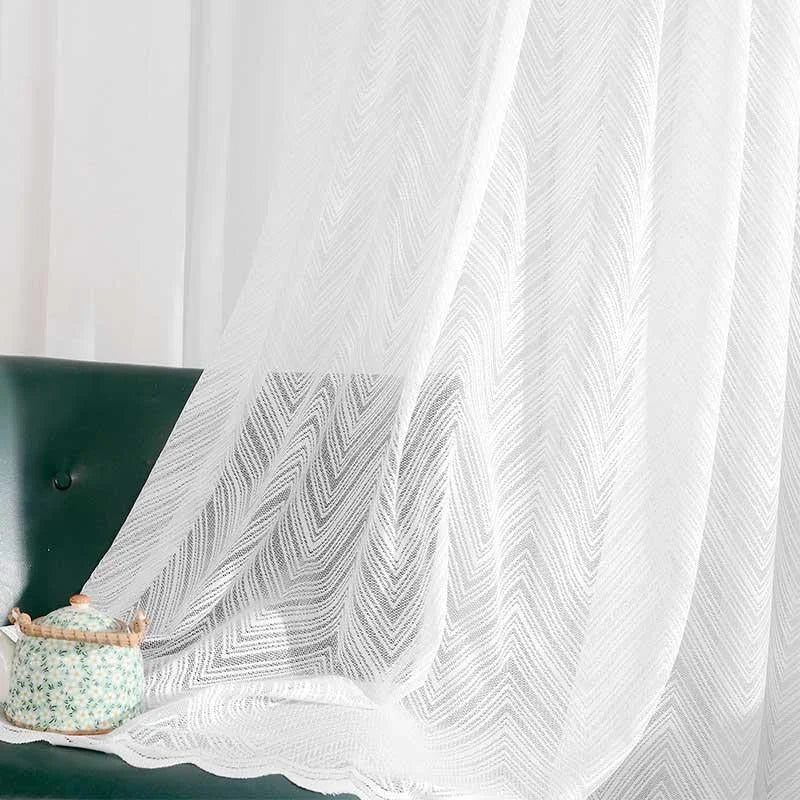 Voilage blanc transparent à motif chevron, idéal pour une décoration intérieure élégante et moderne. Parfait pour habiller les fenêtres et laisser entrer la lumière naturelle, ce voilage offre un style raffiné à votre salon. Le contraste avec un fauteuil vert foncé ajoute une touche de chic à votre ambiance.