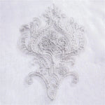 Broderie élégante sur fond blanc, motif complexe et raffiné, idéal pour personnaliser des textiles et ajouter une touche d'élégance à votre décoration intérieure. Adapté pour les projets de couture créative et les embellissements luxueux.