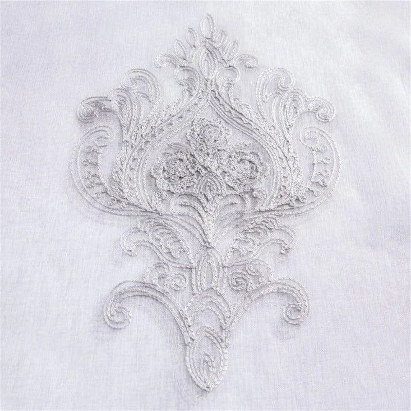 Broderie élégante sur fond blanc, motif complexe et raffiné, idéal pour personnaliser des textiles et ajouter une touche d'élégance à votre décoration intérieure. Adapté pour les projets de couture créative et les embellissements luxueux.