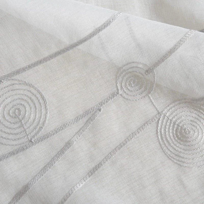 Voilage blanc avec motifs géométriques en spirale, idéal pour apporter une touche moderne et élégante à votre intérieur. Ce rideau lumineux et design s'intègre parfaitement dans tout type de décoration. Parfait pour réguler la lumière tout en préservant votre intimité.