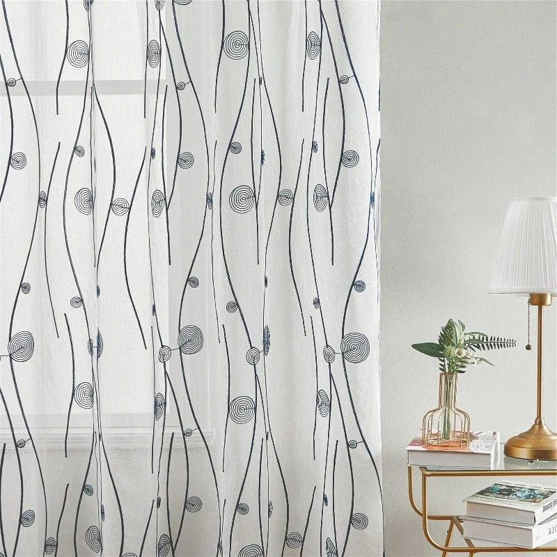 Voilage décoratif avec motifs modernes en spirale, idéal pour ajouter une touche d'élégance à votre intérieur. Parfait pour les salons ou les chambres, ce rideau apportera une ambiance légère et sophistiquée. Accessoirisé avec une lampe design et des livres pour un espace de vie harmonieux.