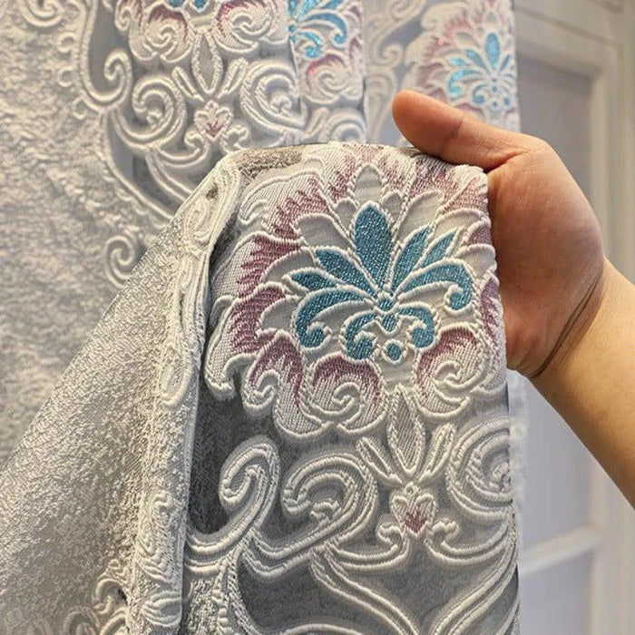 Rideau élégant avec motif floral en filigrane, accentué de nuances bleues et roses. Design classique et raffiné idéal pour embellir un salon ou une chambre. Parfait pour ajouter une touche de sophistication à votre décoration intérieure.