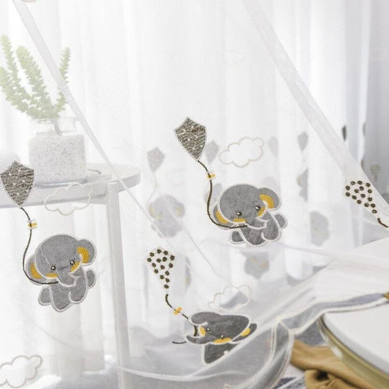 Rideau enfant avec motifs animaux, éléphants gris volant avec des cerfs-volants sur fond blanc, parfait pour décorer une chambre de bébé ou une chambre d'enfant. Crée une ambiance ludique et apaisante tout en laissant passer la lumière naturelle. Adapté pour une décoration moderne et fun.