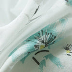Gros plan sur un tissu floral blanc et turquoise, idéal pour des créations de mode élégantes et modernes. Motif floral délicat, parfait pour apporter une touche de fraîcheur et de douceur à vos projets textiles.