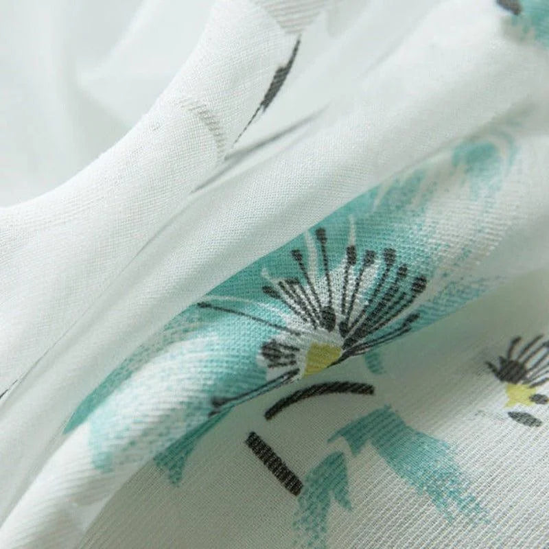 Gros plan sur un tissu floral blanc et turquoise, idéal pour des créations de mode élégantes et modernes. Motif floral délicat, parfait pour apporter une touche de fraîcheur et de douceur à vos projets textiles.