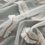 Tissu transparent avec des motifs brodés blancs et beiges, parfait pour la confection de vêtements élégants ou de décorations délicates. Design raffiné apportant une touche de sophistication à vos créations couture. Idéal pour robes, voilages ou accessoires de mode.