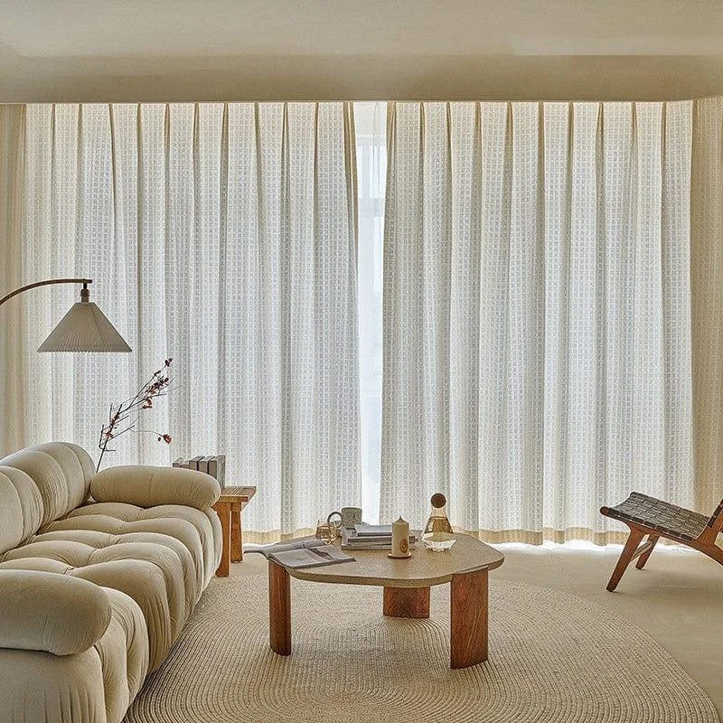 Salon moderne avec canapé confortable, table basse design et rideaux élégants créant une ambiance chaleureuse et lumineuse. Décoration intérieure contemporaine accentuée par un éclairage doux et un tapis circulaire. Espace de détente idéal pour un intérieur stylé.