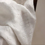 Image d'un tissu blanc à motif texturé, idéal pour la décoration intérieure, parfait pour apporter une touche d'élégance et de luminosité à votre espace.