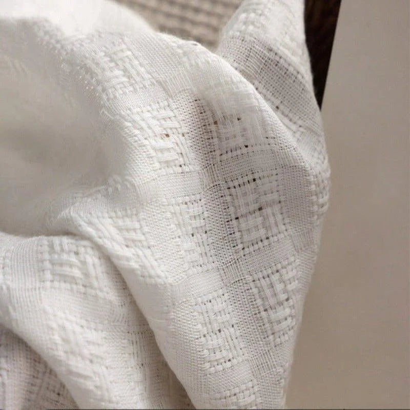 Image d'un tissu blanc à motif texturé, idéal pour la décoration intérieure, parfait pour apporter une touche d'élégance et de luminosité à votre espace.