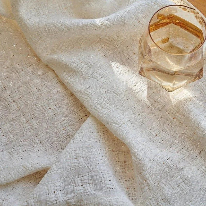 Tissu blanc texturé avec motif géométrique délicat, accompagné d'un verre facetté élégant, idéal pour décorer et embellir votre espace de vie avec une touche de raffinement.