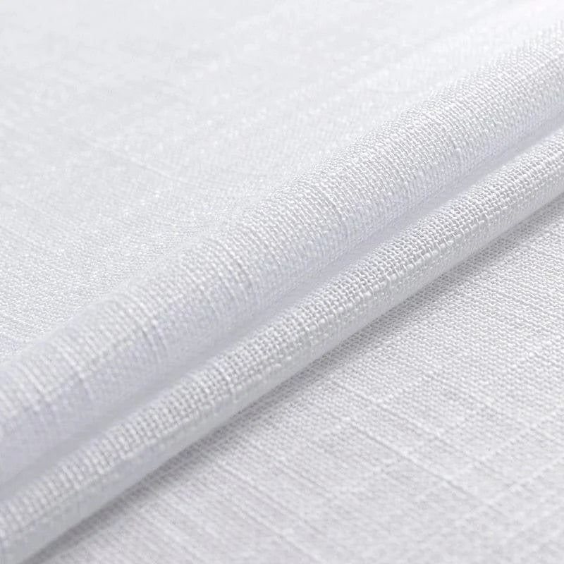 Gros plan sur un tissu blanc texturé, idéal pour la décoration intérieure et la confection de rideaux ou nappes. Design élégant et sobre, parfait pour ajouter une touche moderne et épurée à votre espace.