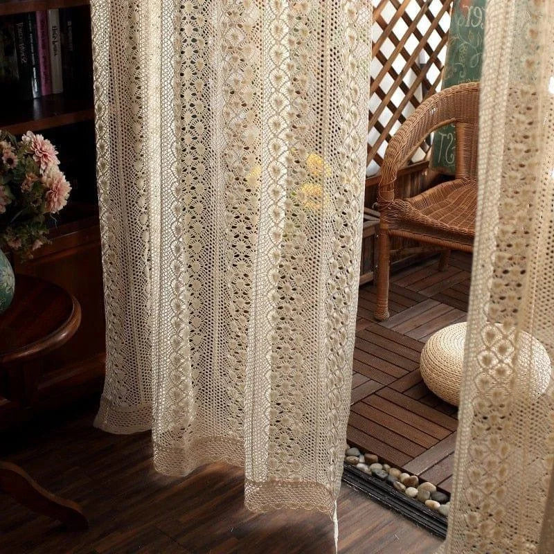 Rideau décoratif beige au design ajouré pour intérieur raffiné, parfait pour ajouter une touche élégante à votre salon ou terrasse. Idéal pour filtrer la lumière tout en offrant une ambiance chaleureuse et accueillante. Se marie harmonieusement avec une chaise en osier et d'autres éléments naturels pour un espace de détente stylé.