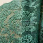 Tissu vert délicat avec motifs floraux destinés à la confection de vêtements élégants, idéal pour la couture de robes de soirée chic et féminines, ajoutant une touche de sophistication à toute création vestimentaire.