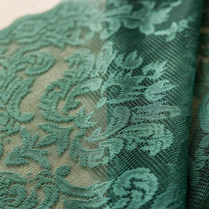 Tissu vert délicat avec motifs floraux destinés à la confection de vêtements élégants, idéal pour la couture de robes de soirée chic et féminines, ajoutant une touche de sophistication à toute création vestimentaire.