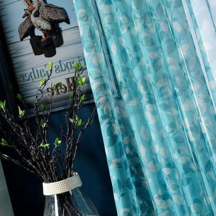 Rideau décoratif bleu à motifs de feuilles pour salon moderne, accompagné d'une déco murale rustique et d'un vase design. Idéal pour ajouter une touche de fraîcheur et d'élégance à votre intérieur.