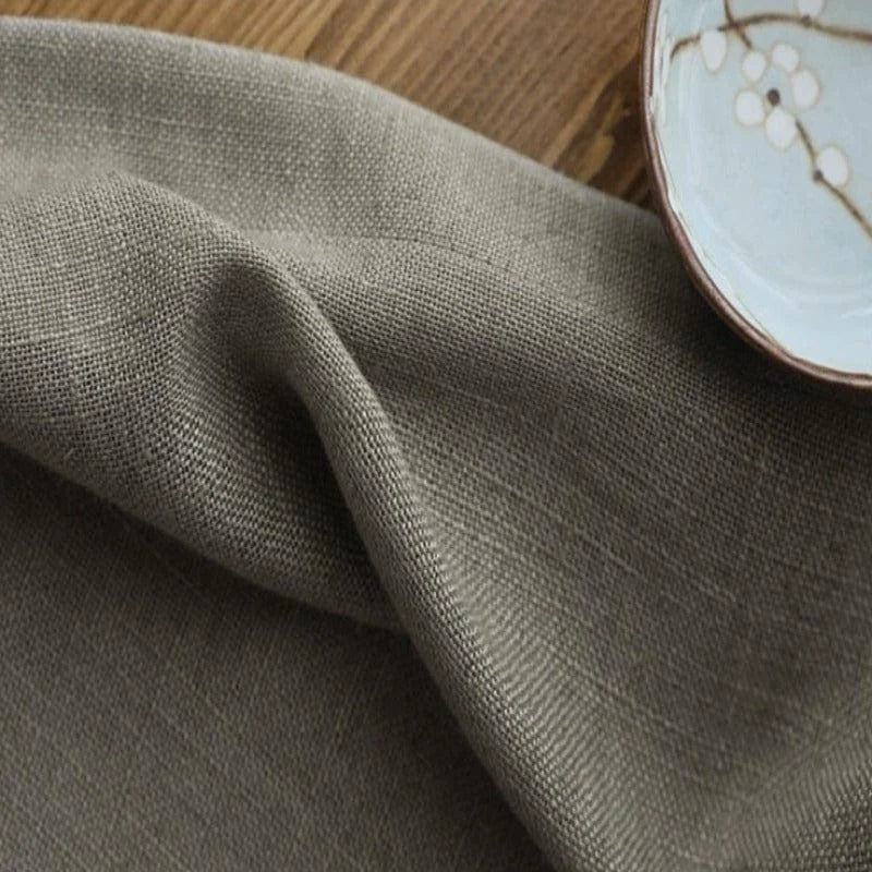 Serviette de table élégante grise posée sur une surface en bois, accompagnée d'une assiette au design floral délicat. Parfaite pour une décoration de table sophistiquée lors de repas en famille ou entre amis.