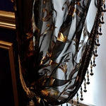 Voilage noir élégant avec motifs dorés et perles en bordure, idéal pour une décoration intérieure raffinée, ajoutant une touche de luxe et de sophistication à votre salon ou chambre. Excellent choix pour créer une ambiance chaleureuse et opulente. Parfait pour les amateurs de design d'intérieur recherchant un élément distinctif et chic.