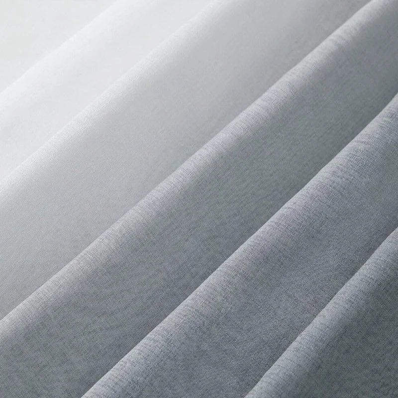 Tissu gris et blanc en gros plan, présentant des plis élégants. Parfait pour des créations de mode ou d'intérieur, ce textile offre une esthétique moderne et épurée. L'alternance des teintes apporte une dimension sophistiquée et intemporelle à vos projets de couture et décoration.