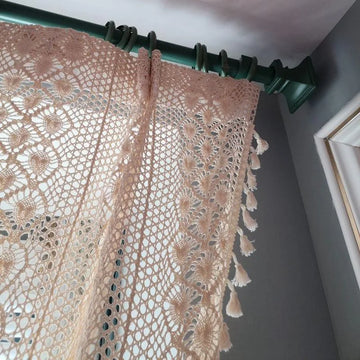 "Rideau élégant au design ajouré et décoratif, suspendu à une tringle verte dans un intérieur moderne. Idéal pour apporter une touche de charme et de lumière naturelle à votre salon ou chambre à coucher."